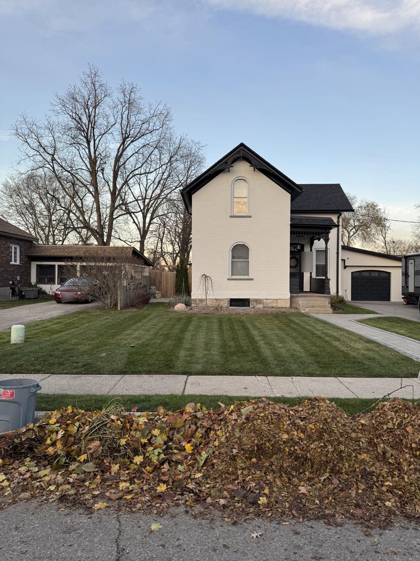 Front lawn freshly cut in stripes with fall leaves raked to the curb