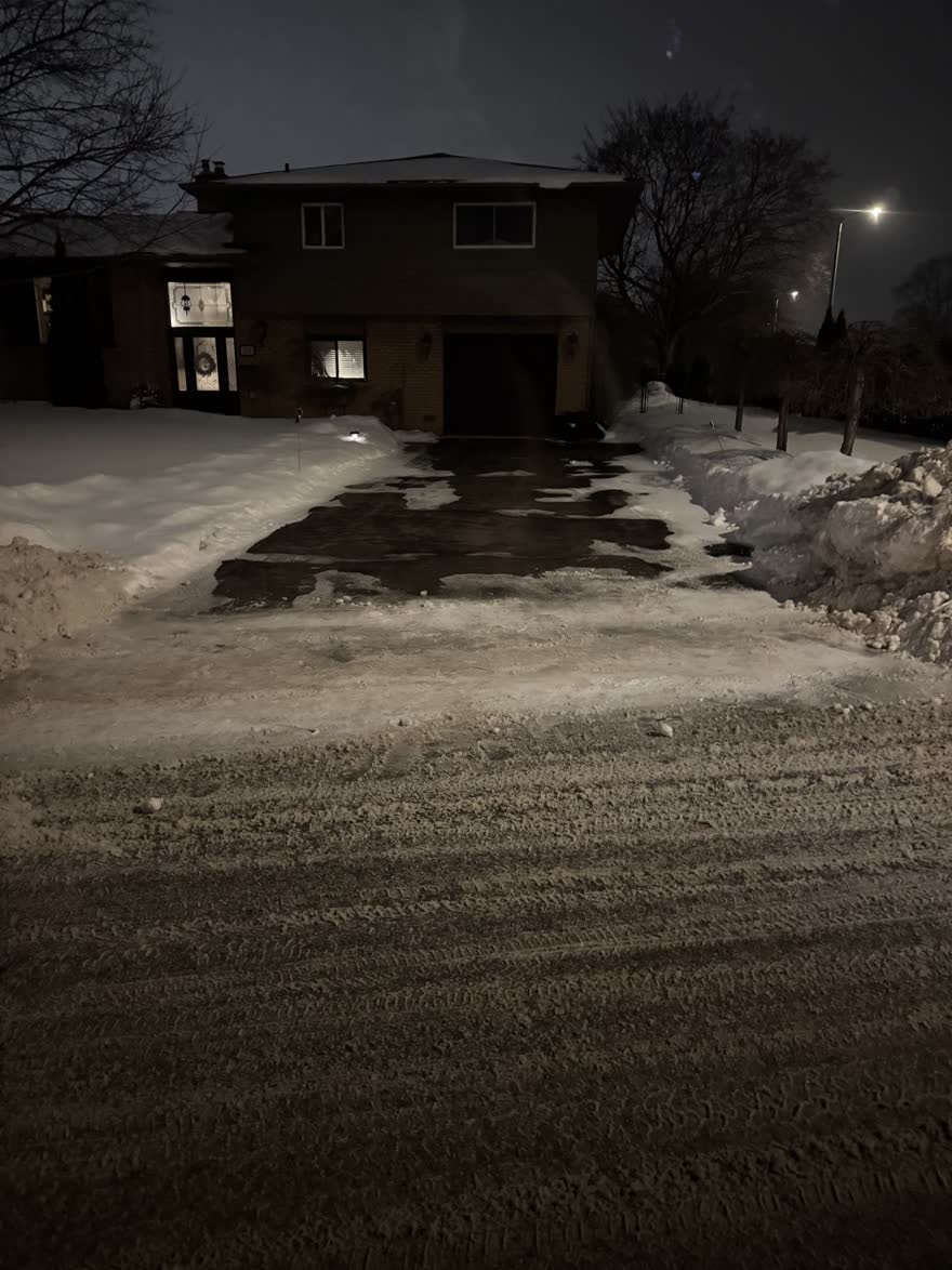 Driveway at night cleared down to pavement, including the windrow at the end of the driveway