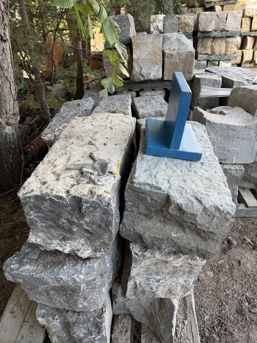 Armour stone pieces with work gloves and a marking block on top, picked out at the stone yard